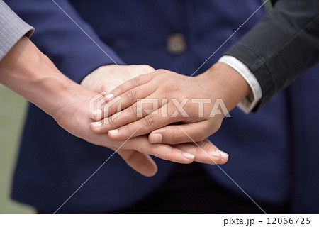 Closed up hand shot of three mixed race business women showing team work by putting hands together Closed up hand shot of three mixed race business women showing team work by putting hands together 12066725