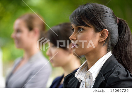 Team leader of 3 young successful mixed race business women standing along green walkway Team leader of 3 young successful mixed race business women standing along green walkway 12066726