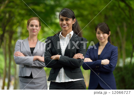 Team leader of 3 young successful mixed race business women standing along green walkway Team leader of 3 young successful mixed race business women standing along green walkway 12066727