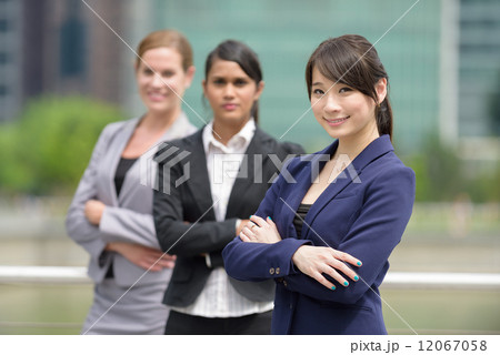 Team leader of 3 young successful mixed race business women standing in front of office building Team leader of 3 young successful mixed race business women standing in front of office building 12067058