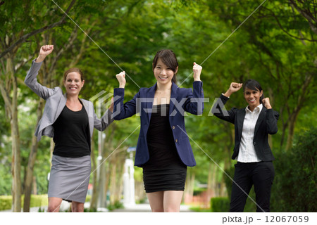 3 victorious young business women celebrating by punching their fist in the air along green walkway 3 victorious young business women celebrating by punching their fist in the air along green walkway 12067059
