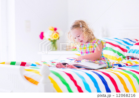 Little girl reading a book in bed Little girl reading a book in bed 12068216