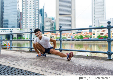 Young asian chinese man stretching / exercising outdoor in the city 12070207