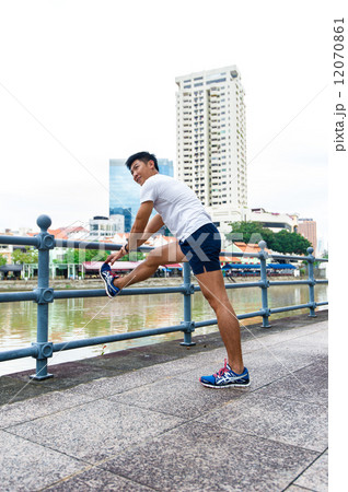 Young and healthy asian male stretching / exercising outdoor in the city 12070861