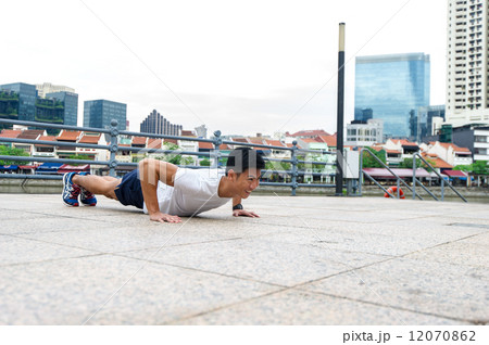 Young and healthy asian male stretching / exercising outdoor in the city 12070862