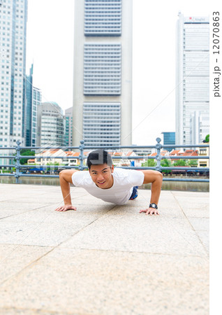 Young and healthy asian male stretching / exercising outdoor in the city 12070863