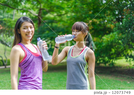 Two young and beautiful ladies taking a break / resting by drinking or hydrating with water 12073749