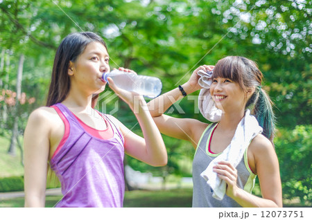 Two young and beautiful ladies taking a break / resting by drinking or hydrating with water 12073751