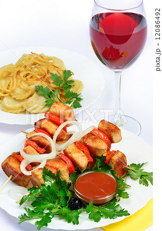 table with food of meat on skewer, dumplings and gass of red win 12086492
