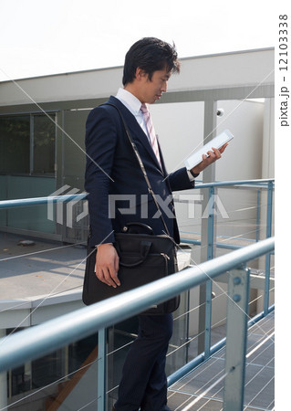 外でタブレットを持つ男性 12103338