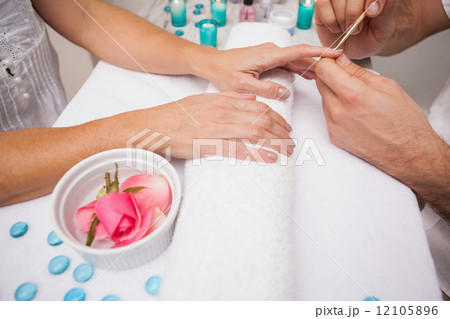 Manicurist cleaning a customers nails Manicurist cleaning a customers nails 12105896