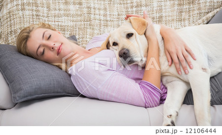 Beautiful blonde on couch with pet dog 12106444