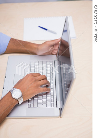 Hands using laptop at desk 12107875
