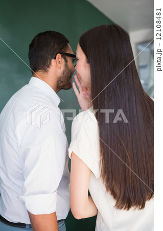 Businesswoman whispering into male colleagues ear 12108481