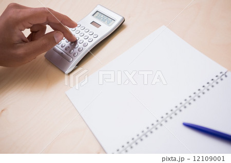 Hand using calculator at desk 12109001