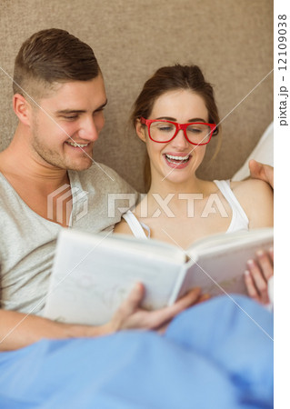 Cute couple reading book in bed Cute couple reading book in bed 12109038