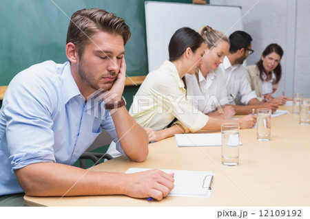 Buisness people working with man sleeping next to them 12109192