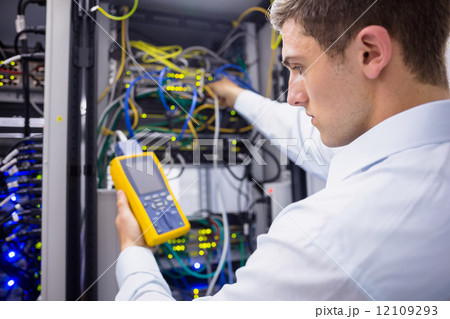 Serious technician using digital cable analyzer on server 12109293