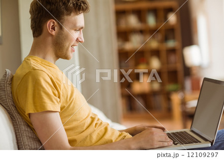 Young man using laptop on his couch 12109297