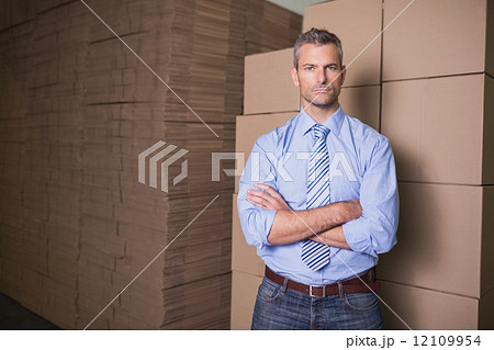 Serious manager with arms crossed in warehouse Serious manager with arms crossed in warehouse 12109954
