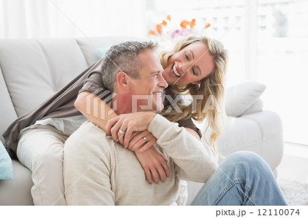 Happy couple sitting and cuddling Happy couple sitting and cuddling 12110074