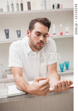 Smiling salon worker with stock book 12110248