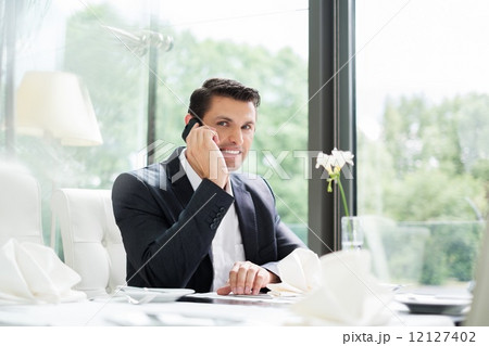 Handsome businessman talking over mobile phone in restaurant 12127402