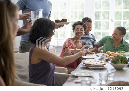 A family gathering; men; women and children around a dining table sharing a meal. 12130924