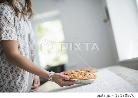 A woman carrying food to a table, preparing for a family meal. 12130976