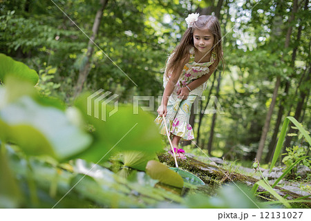 A girl playing at a pond in a forest. 12131027