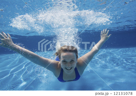 A young girl with long hair fanning out in the water, swimming underwater. 12131078