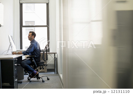 Office life. A man in casual clothing seated at a desk looking at a computer screen. Office life. A man in casual clothing seated at a desk looking at a computer screen. 12131110