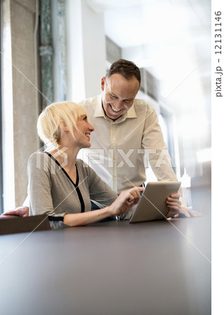 Office life. Two people sharing a digital table in an office. 12131146
