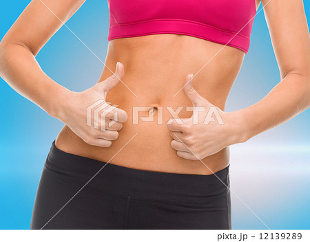 close up of female abs and hands showing thumbs up 12139289