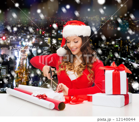 smiling woman in santa helper hat packing gift box smiling woman in santa helper hat packing gift box 12140044