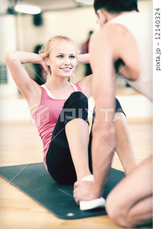 male trainer with woman doing sit ups in the gym male trainer with woman doing sit ups in the gym 12140324