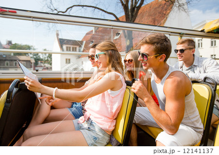group of smiling friends traveling by tour bus 12141137