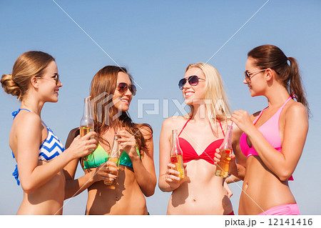 group of smiling young women drinking on beach group of smiling young women drinking on beach 12141416