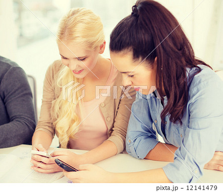 two teens with smartphones at school 12141479