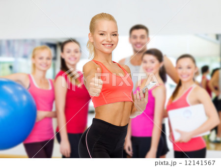 smiling sporty woman with smartphone 12141567