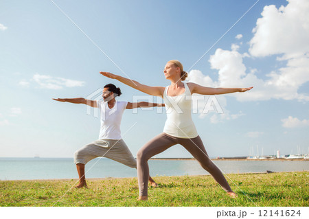 smiling couple making yoga exercises outdoors smiling couple making yoga exercises outdoors 12141624