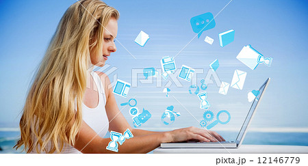 Composite image of pretty blonde using her laptop at the beach 12146779