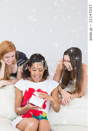 Composite image of cheerful young women surprising friend with a Composite image of cheerful young women surprising friend with a 12147037