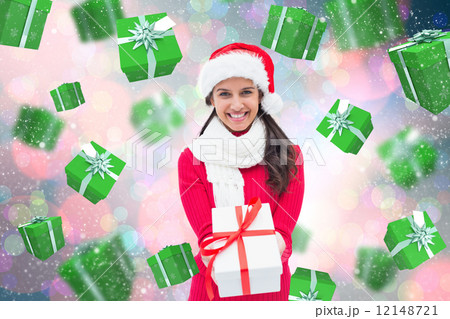 Composite image of festive brunette holding gift 12148721