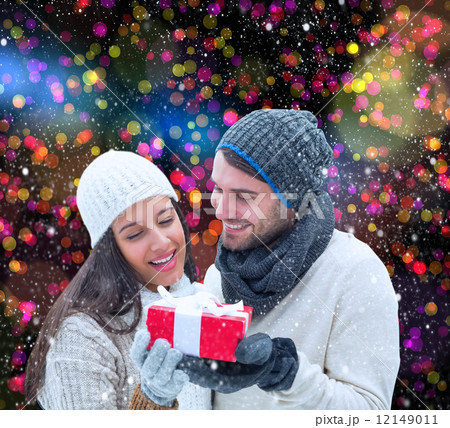 Composite image of winter couple holding gift 12149011