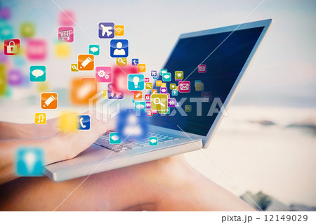 Composite image of woman sitting on beach using her laptop 12149029