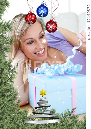 Cheerful blond woman holding a present lying on the floor Cheerful blond woman holding a present lying on the floor 12149379