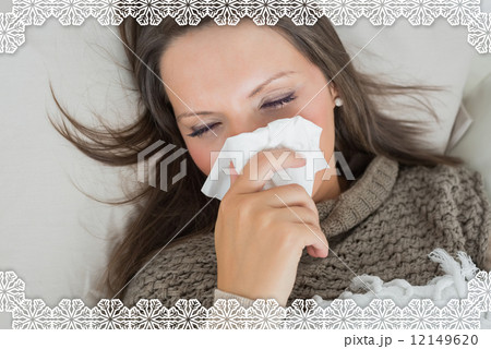 Sick woman lying on sofa and blowing nose 12149620