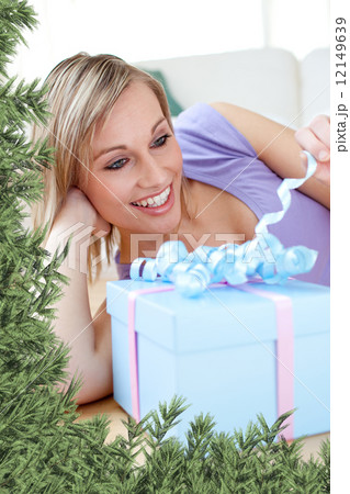 Cheerful blond woman holding a present lying on the floor Cheerful blond woman holding a present lying on the floor 12149639