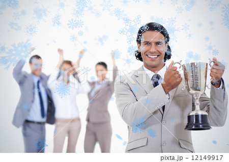 Close up of a man dressed in a suit smiling and holding a cup with people cheerin 12149917